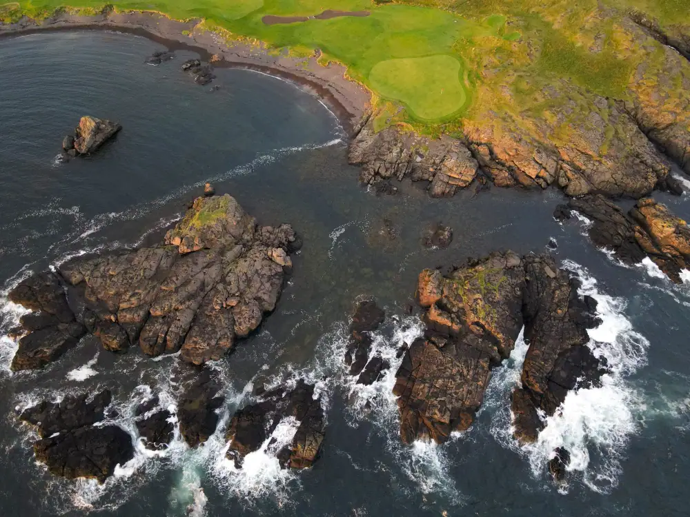 Sea stacks and surf below a green on the cliff